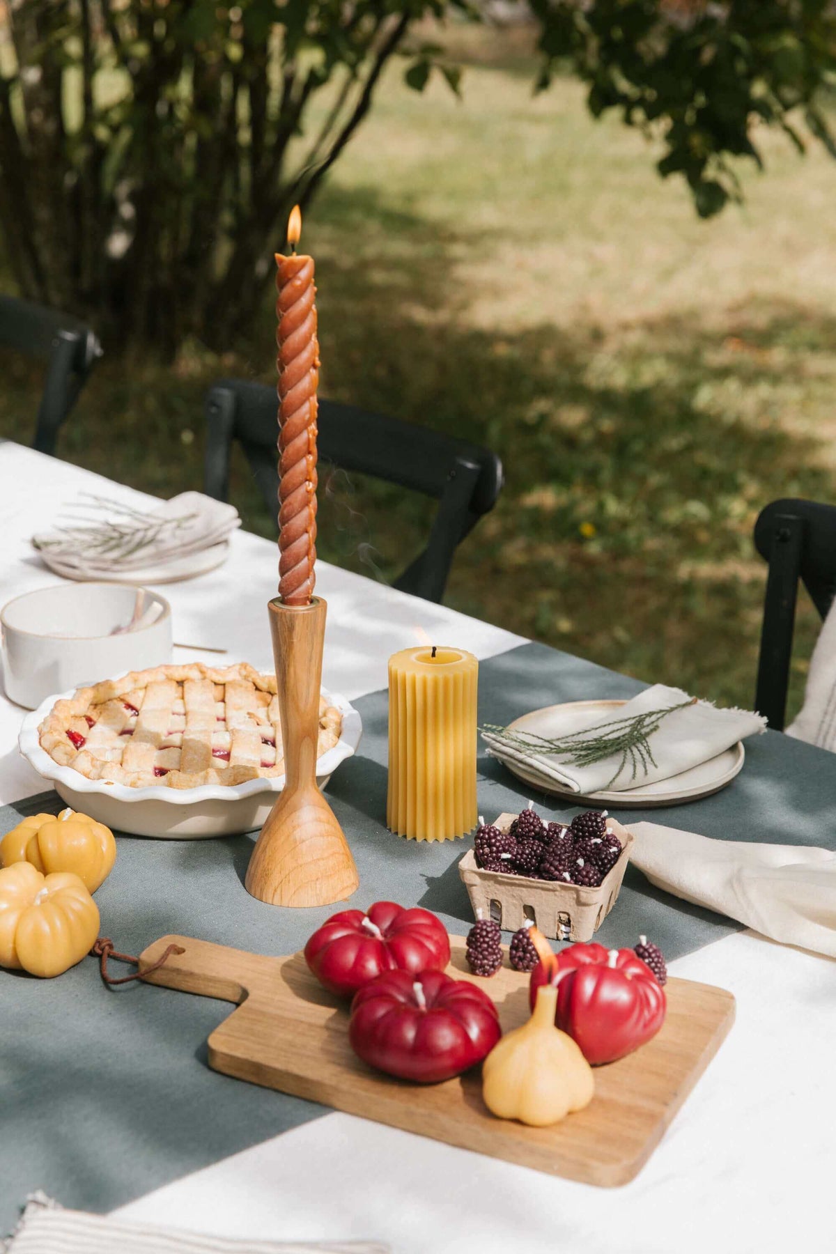 Heirloom tomato candle on a rustic table setting with colorful tomatoes and a candle holder.