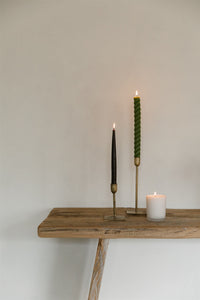 Beeswax taper candles in brass candlesticks on a rustic wooden table